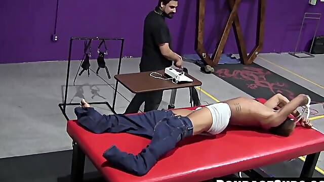 Kaden Roads slaps captive with flogger before jerking his cock