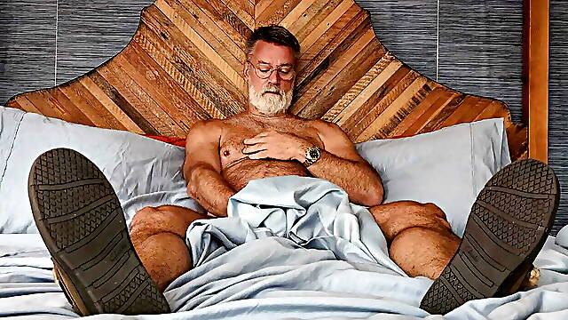 In his bed sniffing his bedroom slippers