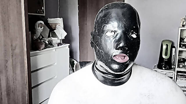 A guy in a latex mask with tubes for his nose jerks off and cums